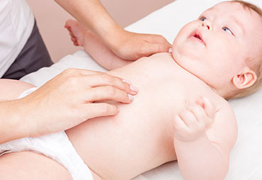 Chiropractor adjusting baby to relieve colic